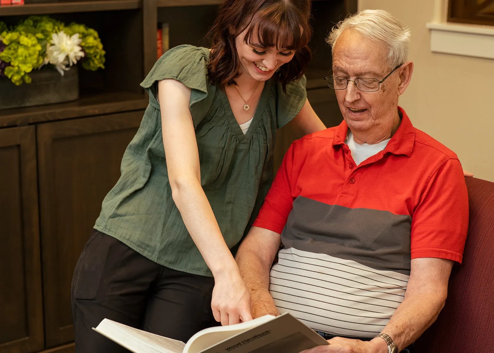 Young woman helping elderly man read book