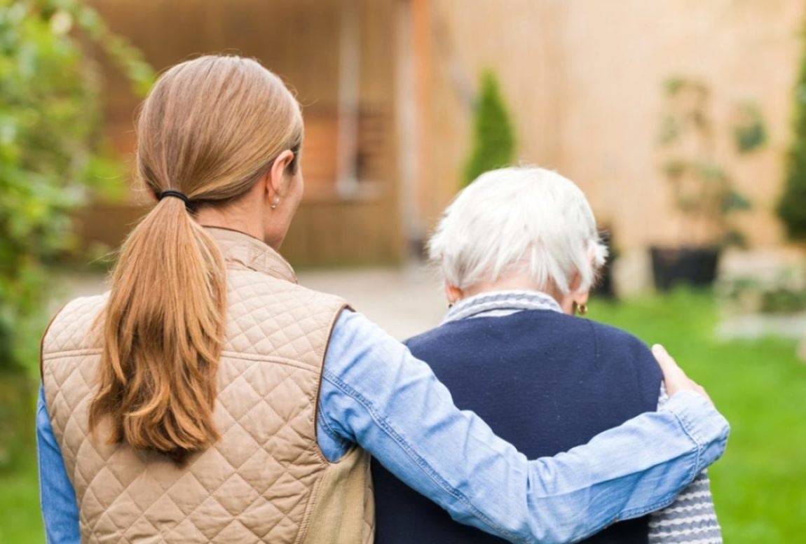 Woman supporting elderly woman in garden