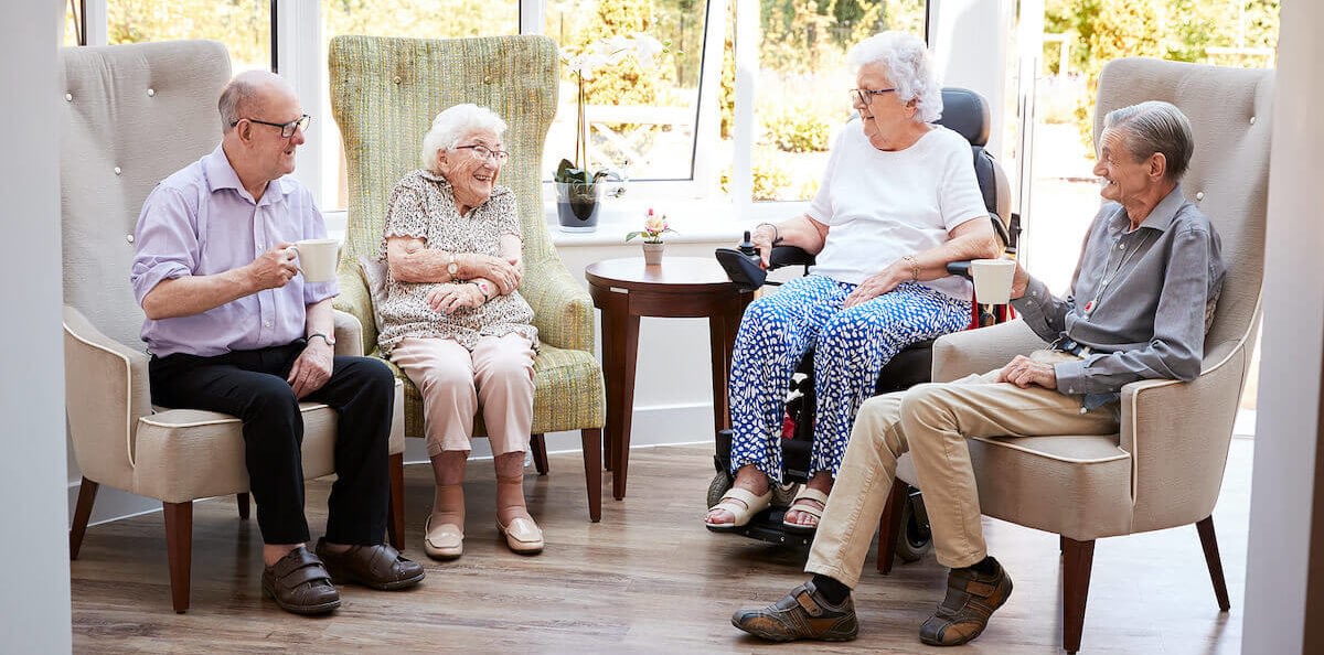 Four seniors chatting in bright living room