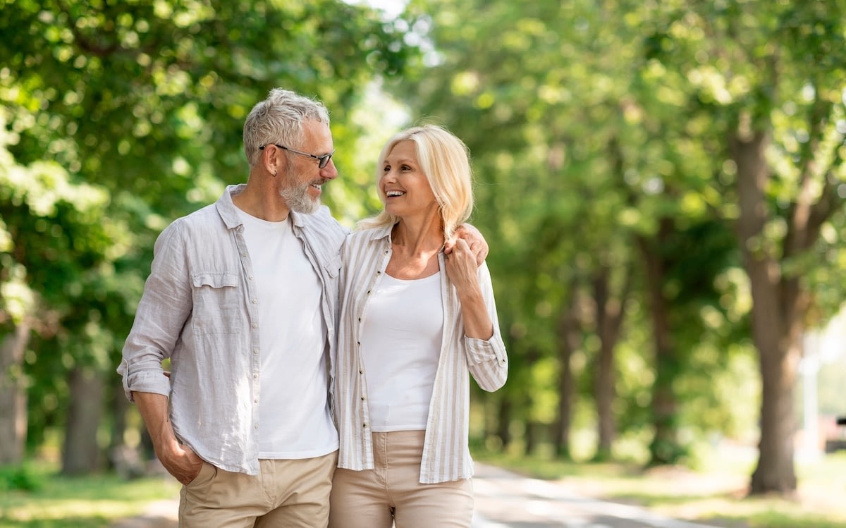 Older couple walking together in sunny park