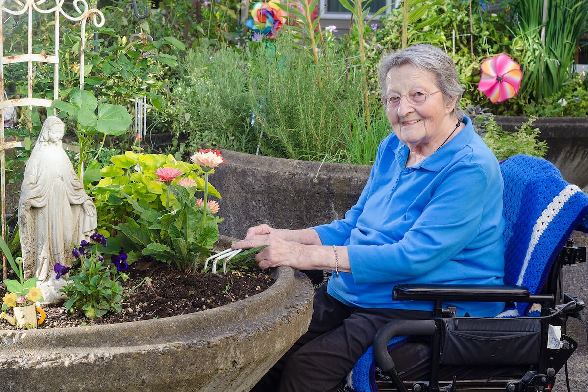 Elderly woman gardening in raised flower bed