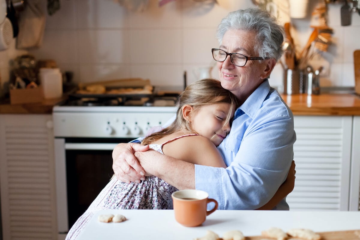 Grandmother hugging granddaughter in cozy kitchen