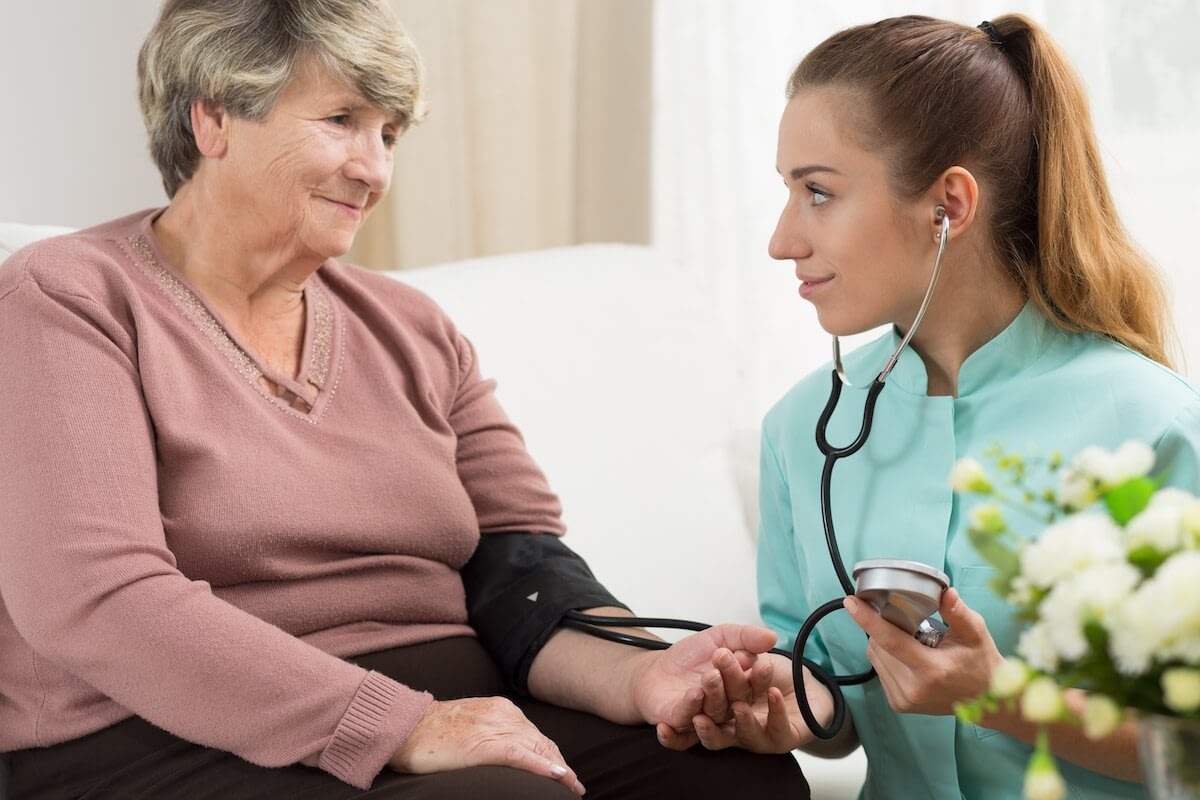 Nurse checking elderly woman's blood pressure at home