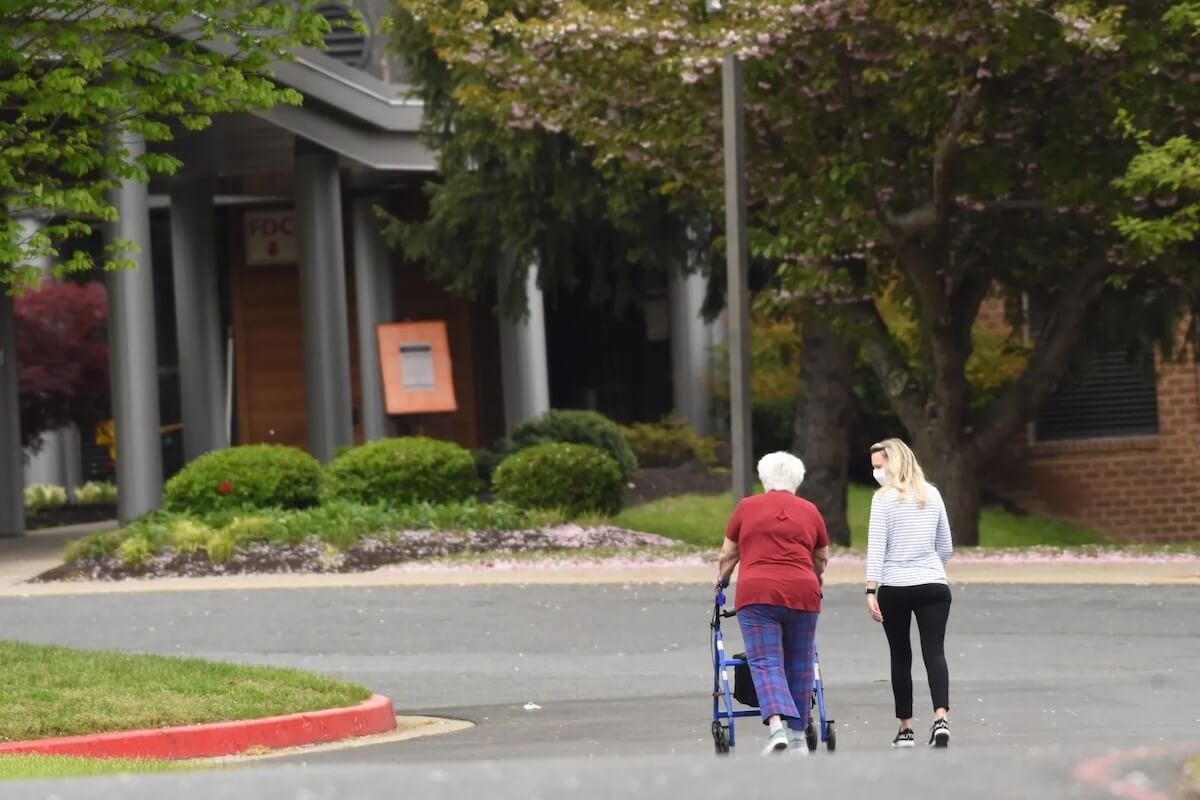 Elderly woman with walker walking beside caregiver