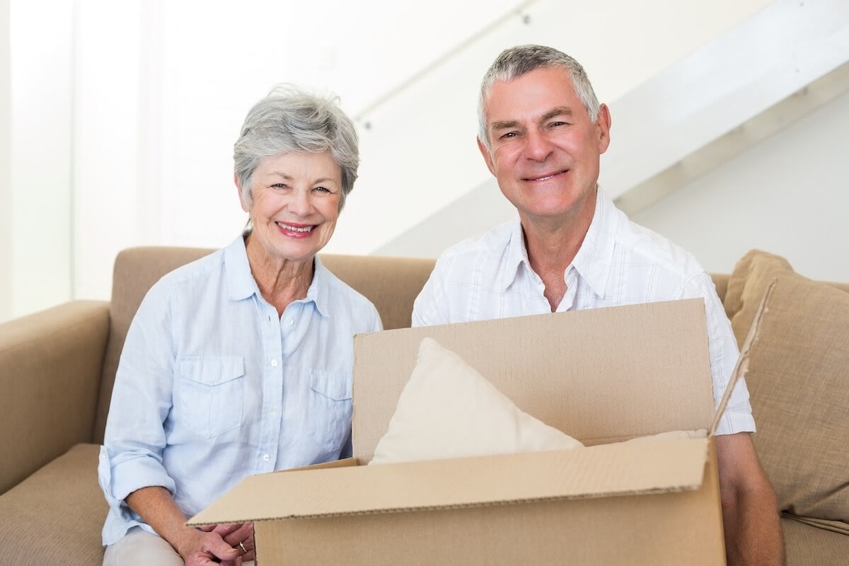 Senior couple unpacking box on living room couch