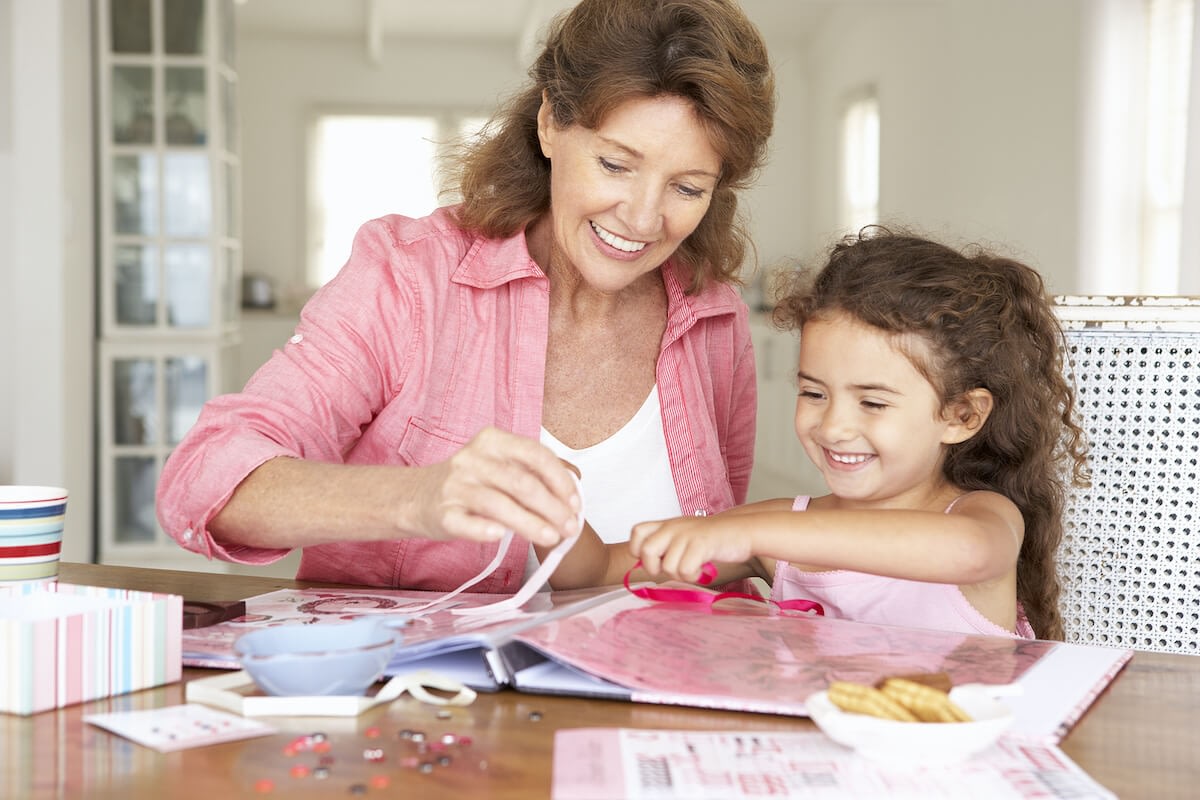 Woman and girl crafting scrapbook at table