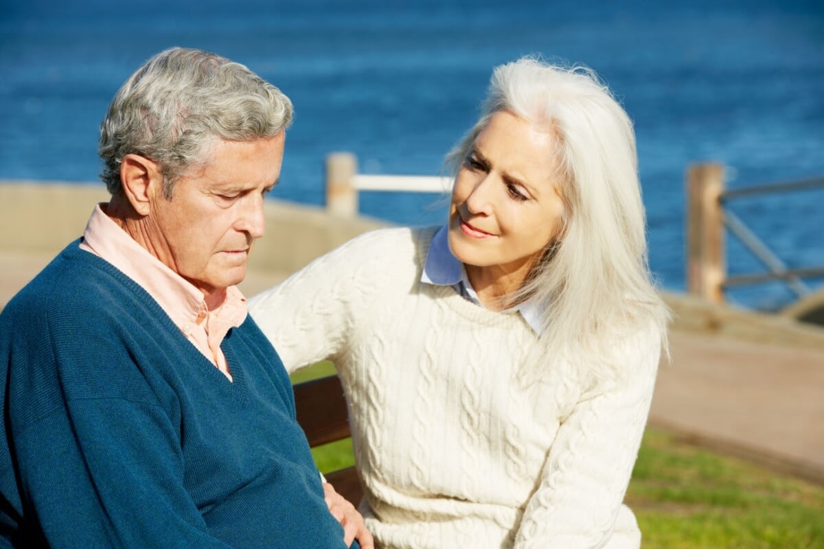 Senior couple sitting on bench by waterfront