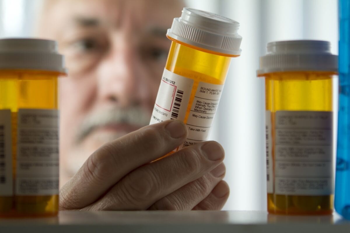 Older man examining prescription pill bottle
