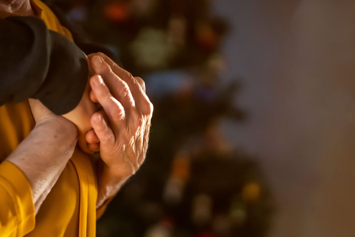 Elderly hands gently holding another person's wrist