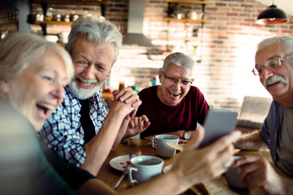 Group of seniors laughing at smartphone together