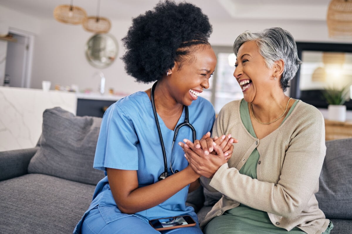 Caregiver and senior woman laughing together at home
