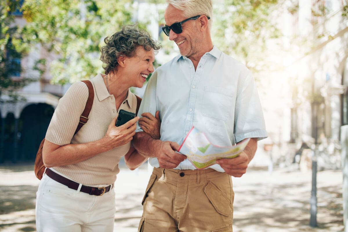 Senior couple smiling with map and smartphone