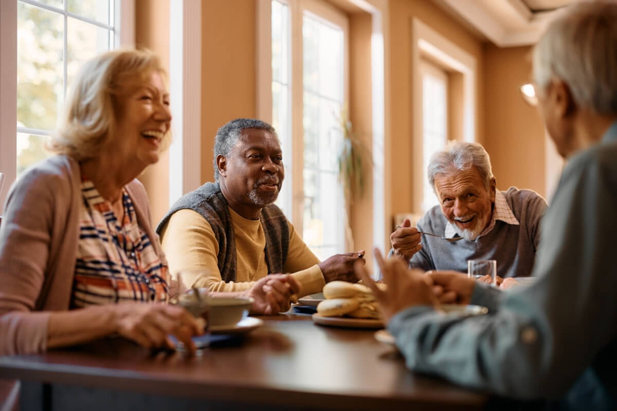 Seniors laughing together at dining table indoors