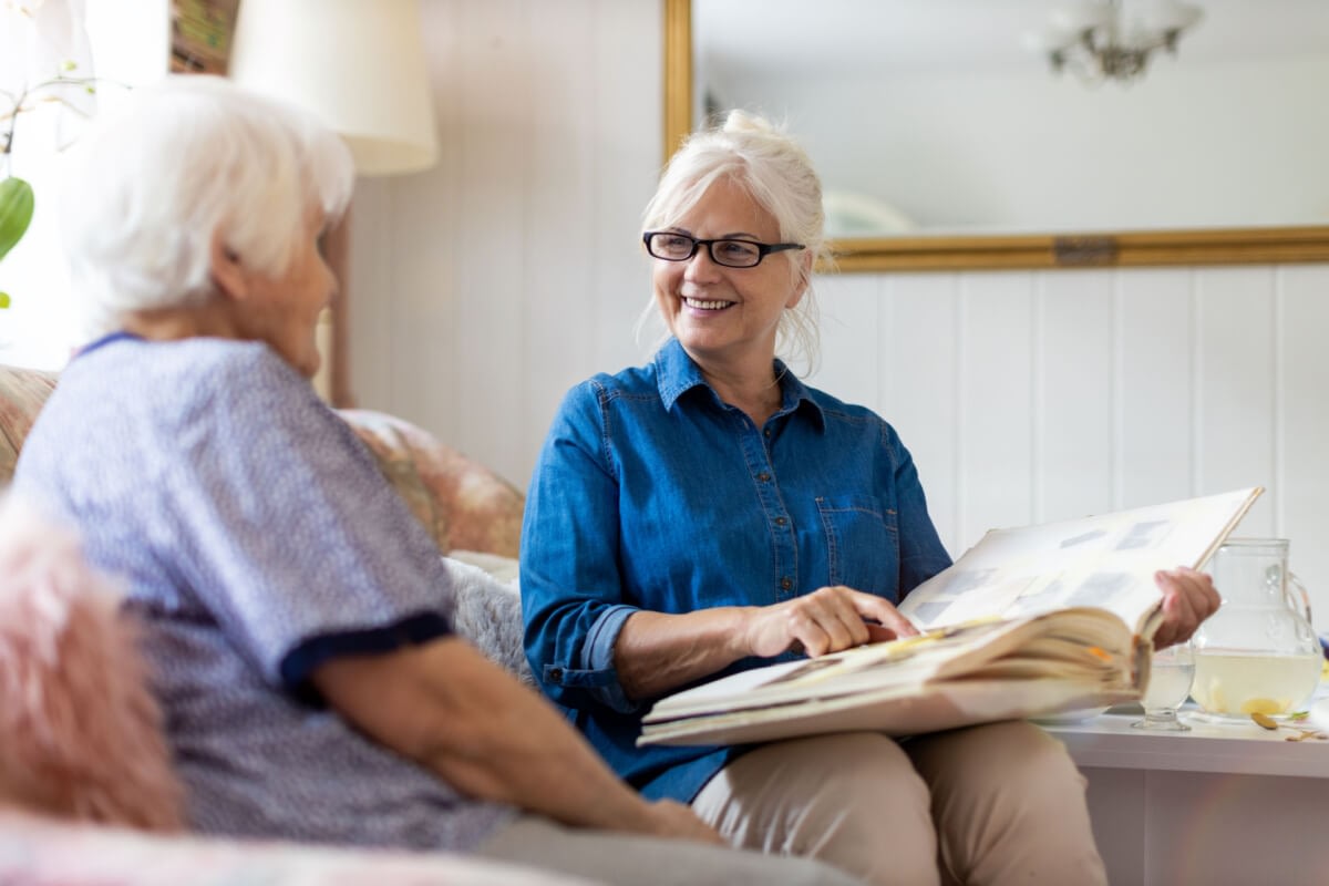 Two elderly women looking at photo album