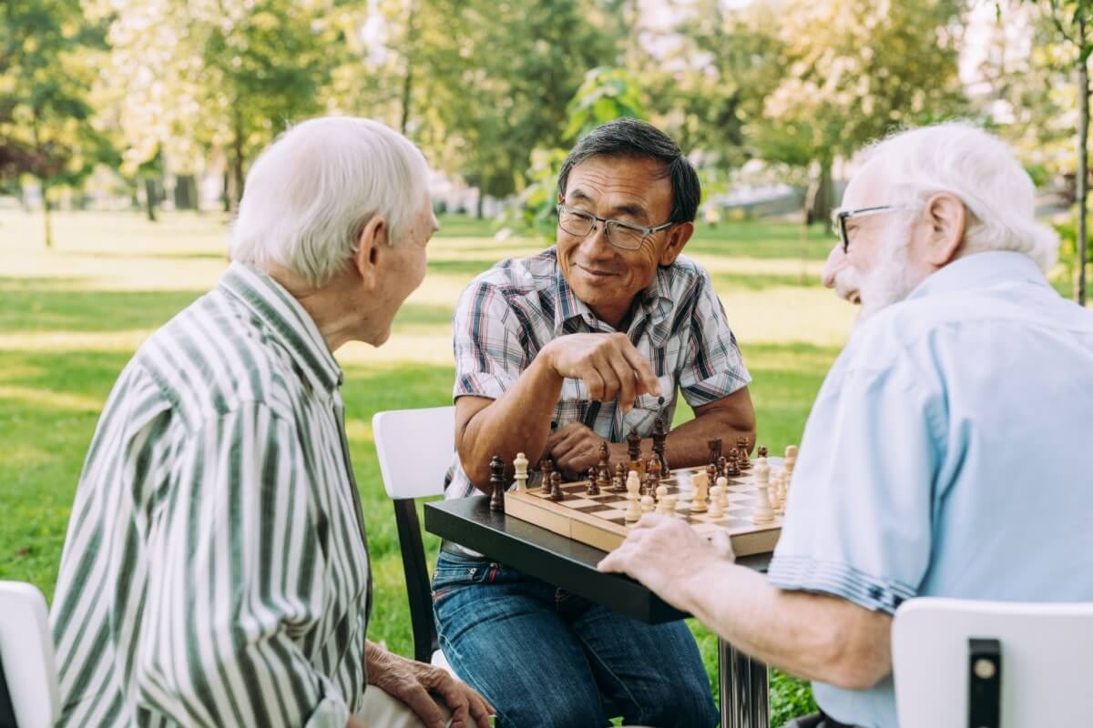 Three elderly men playing chess in park