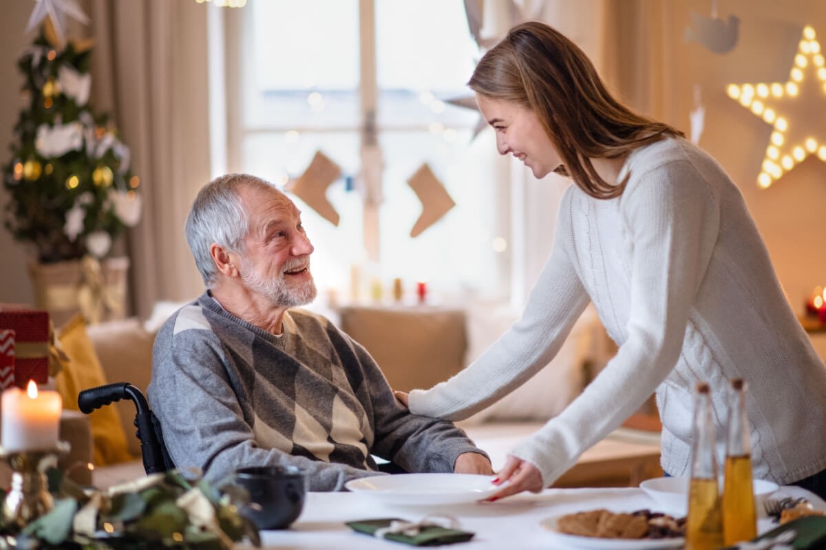 Young woman serving elderly man at holiday dinner