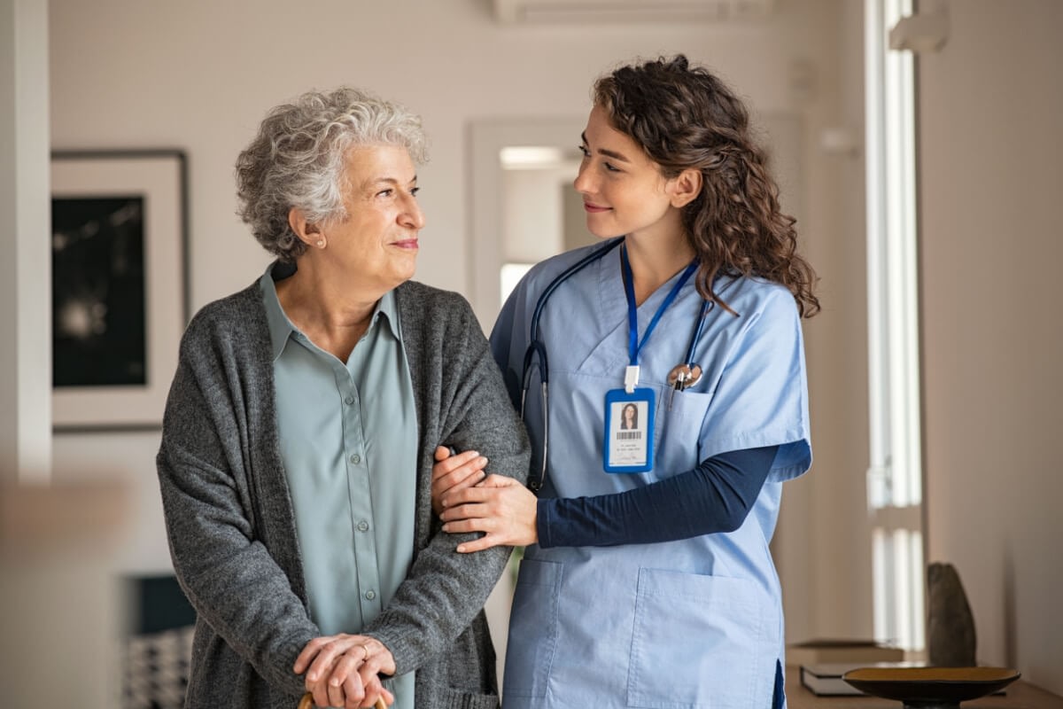 Nurse assisting elderly woman at home