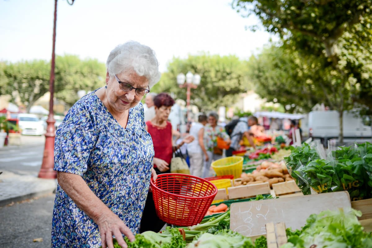 Elderly woman selecting lettuce at outdoor market
