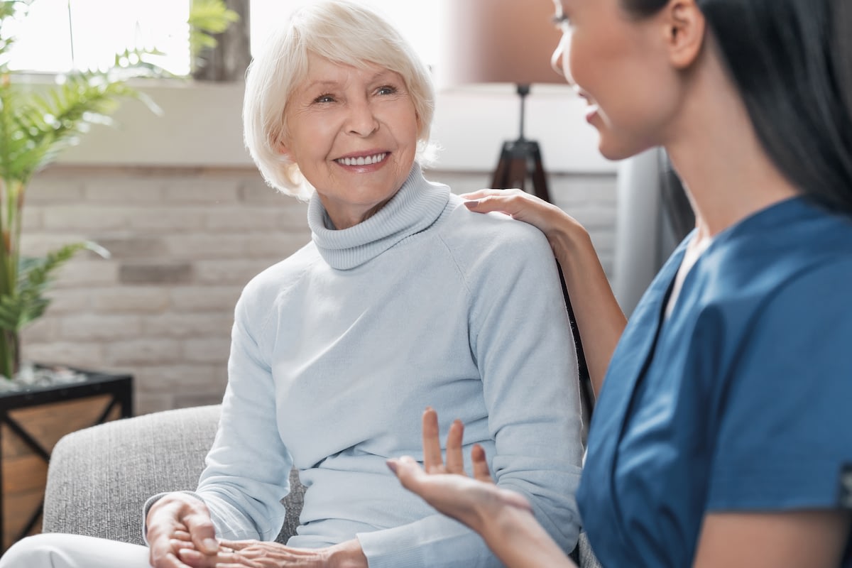Caregiver comforting smiling elderly woman at home