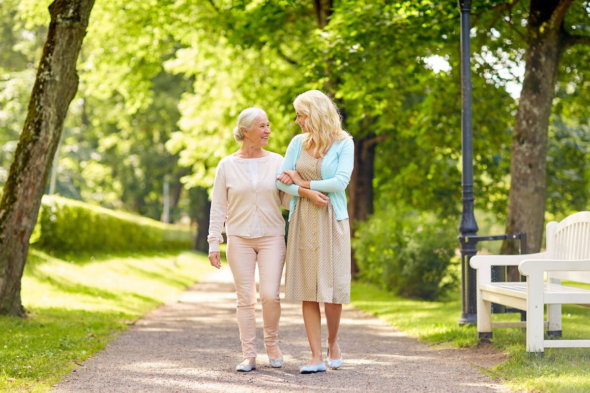Two women walking arm in arm in park