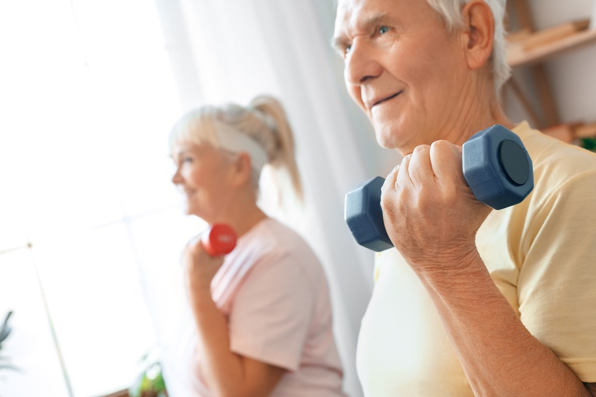Senior couple lifting dumbbells indoors together