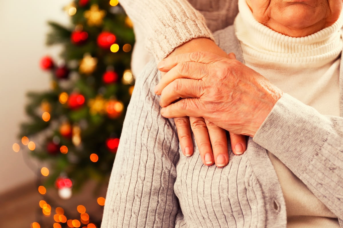 Elderly hands clasped with family at Christmas