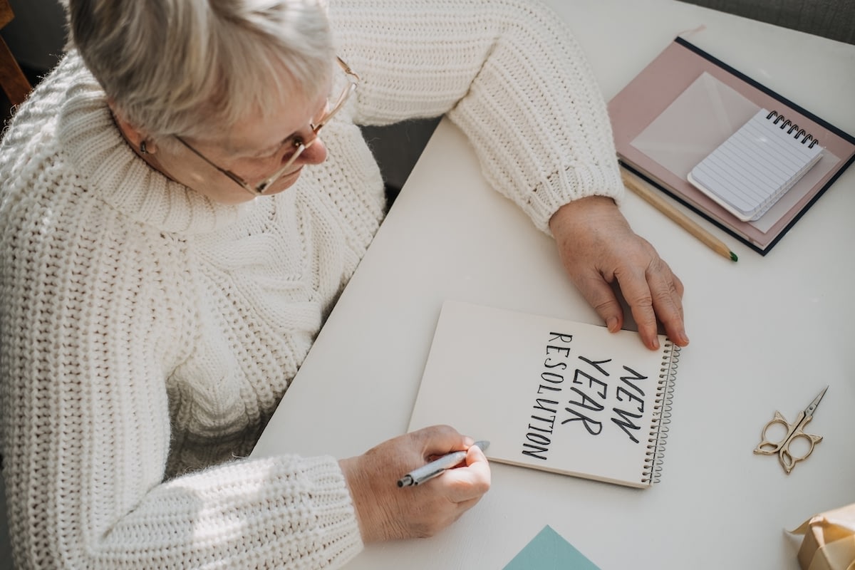Senior woman writing New Year resolutions in notebook