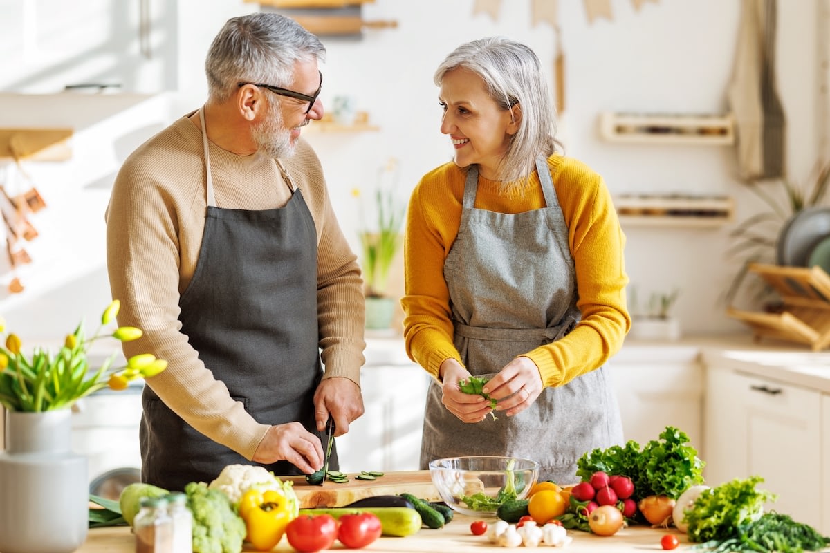 Senior couple cooking fresh vegetables in kitchen