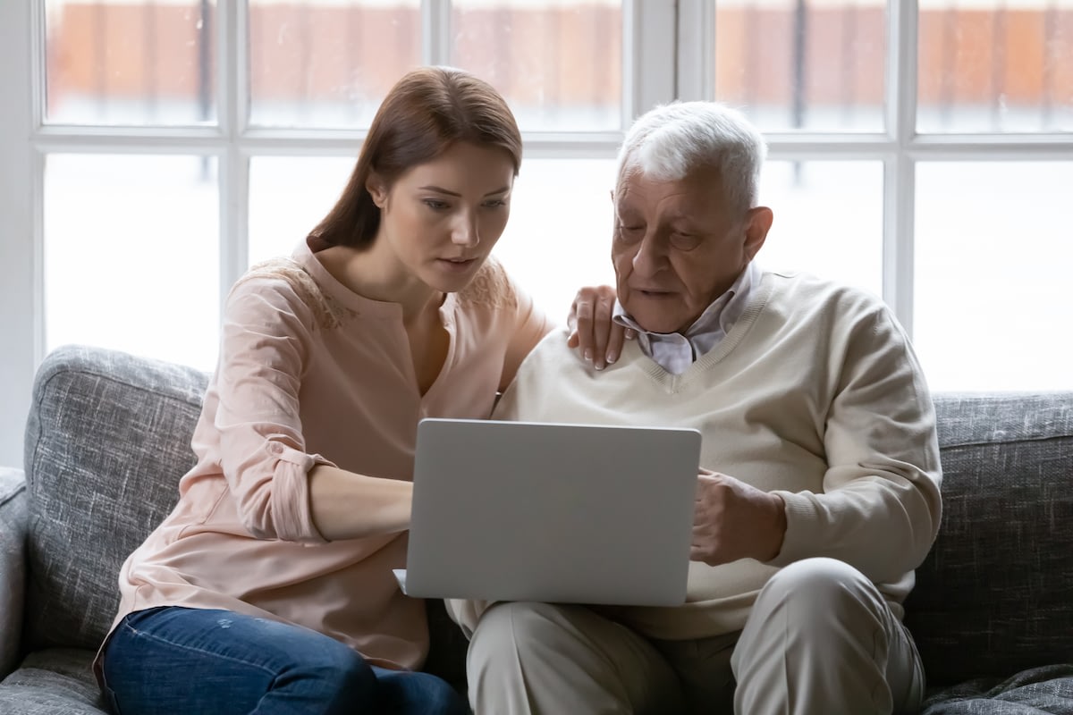 Young woman helping elderly man with laptop