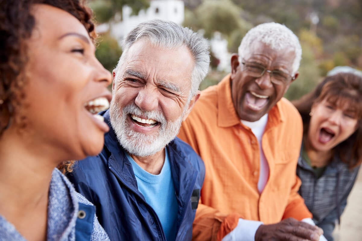 Four older adults laughing together outdoors