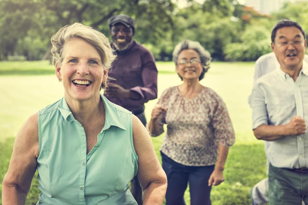 Smiling seniors exercising together in sunny park
