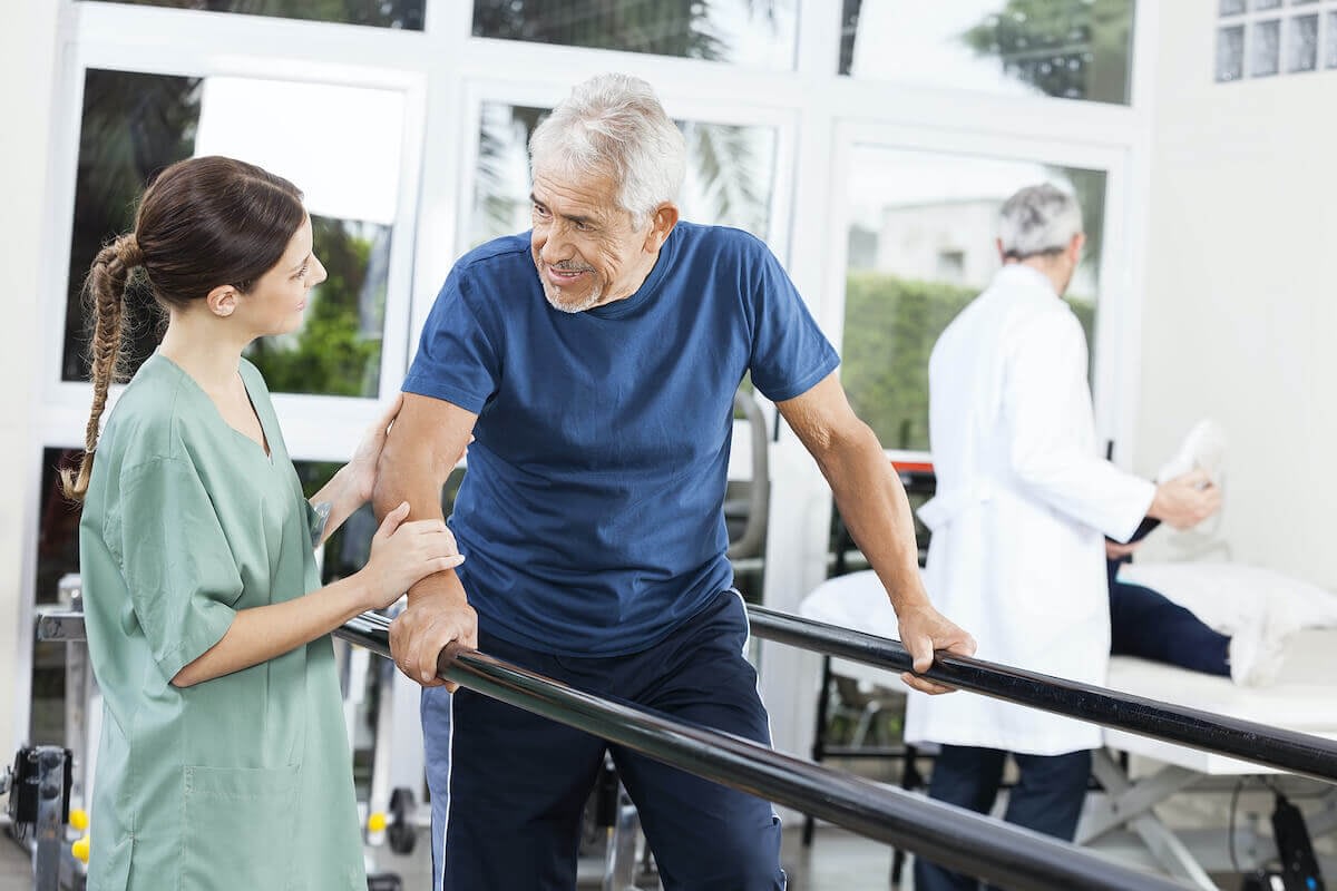 Elderly man walking with therapist during rehabilitation session