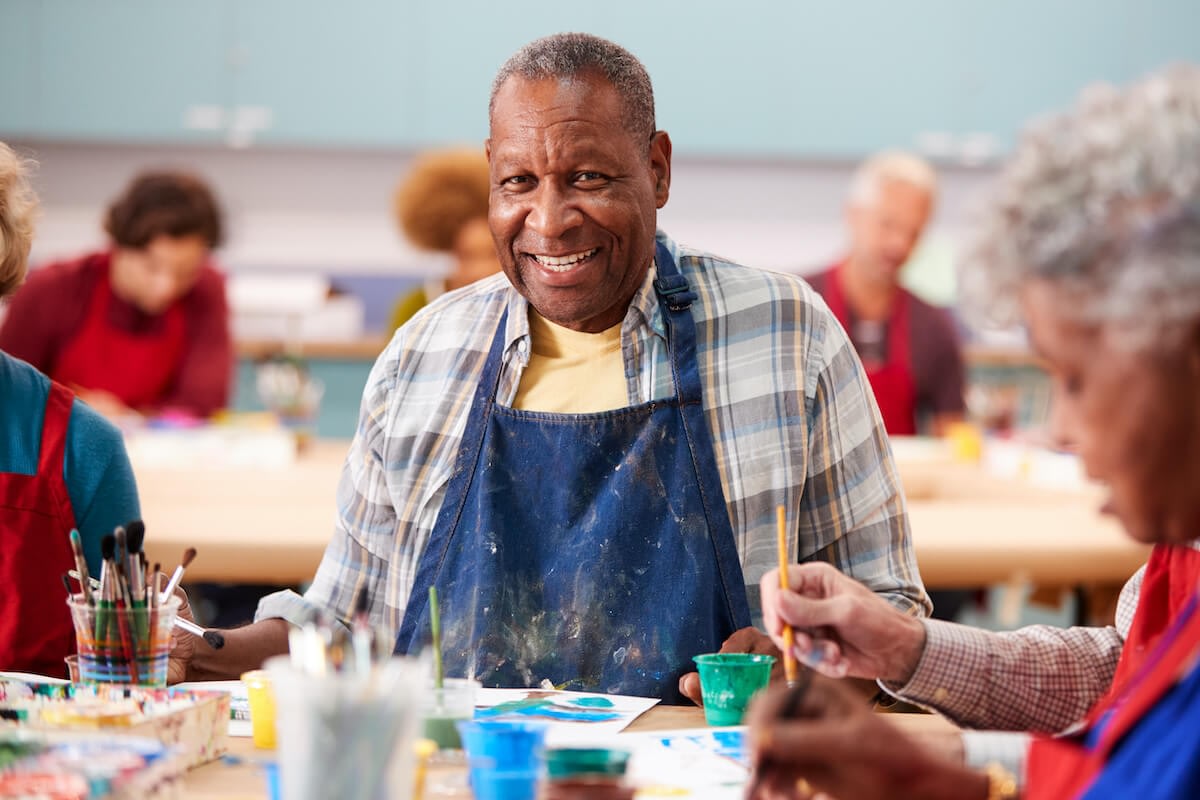 Smiling senior man painting in art class