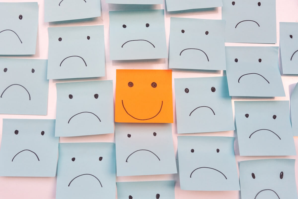 Happy sticky note among sad faces