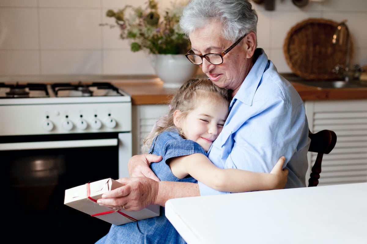 Grandmother hugging granddaughter holding small gift box