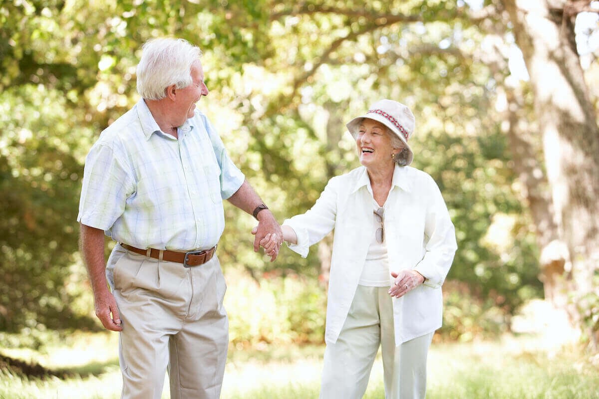 Elderly couple holding hands in sunny park