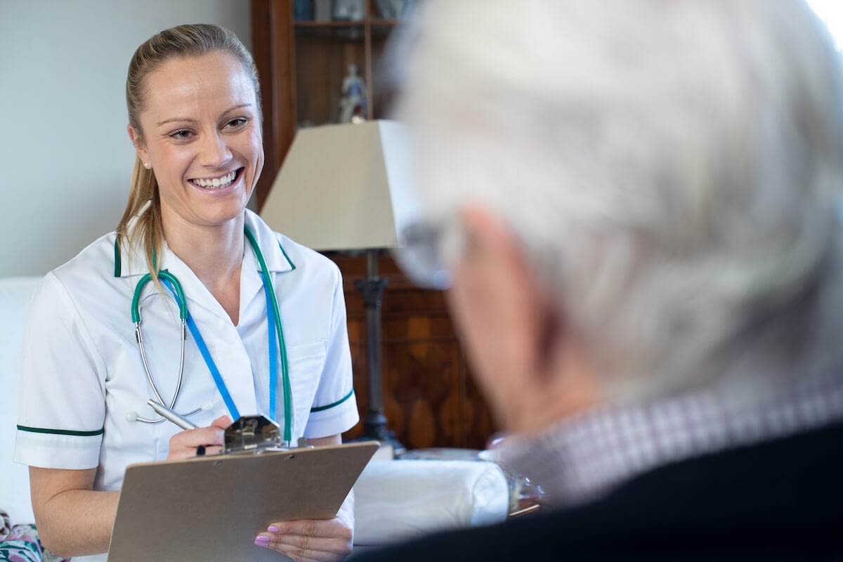 Nurse with stethoscope speaking to elderly patient