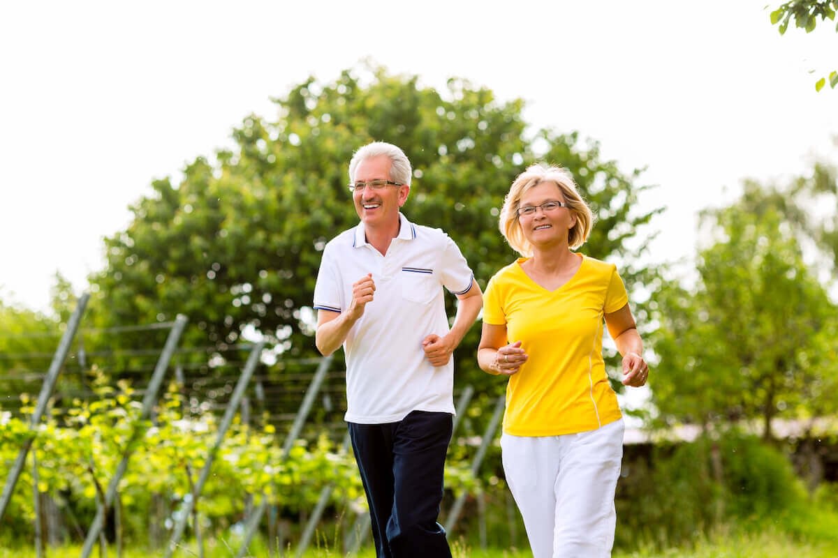 Senior couple jogging outdoors in green park