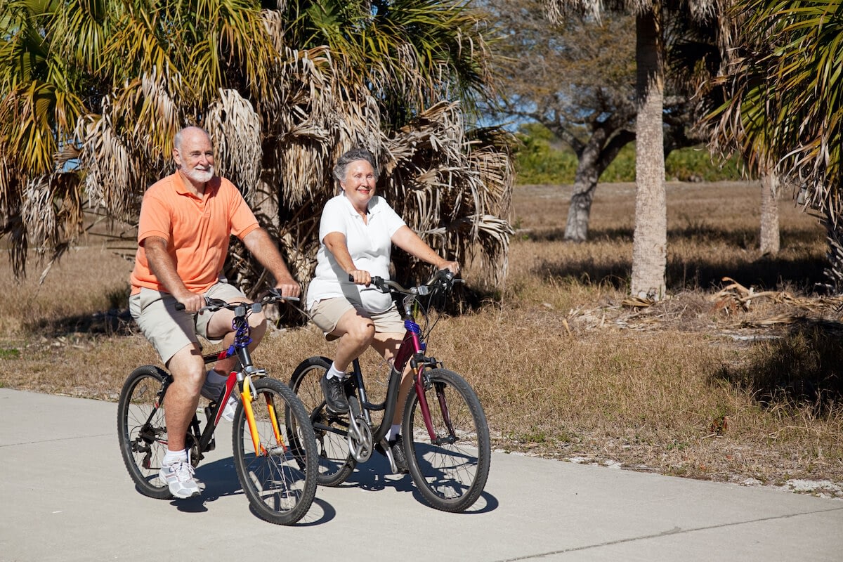 Senior couple riding bicycles on sunny path