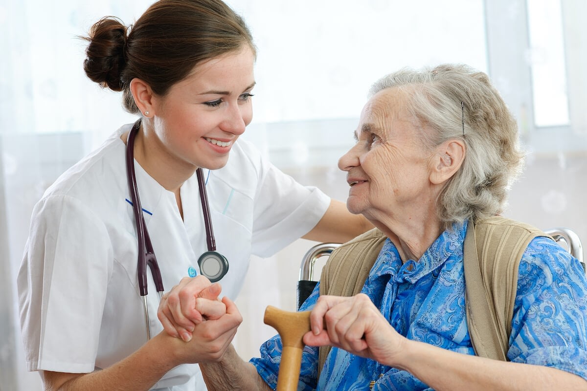 Nurse comforting elderly woman in wheelchair