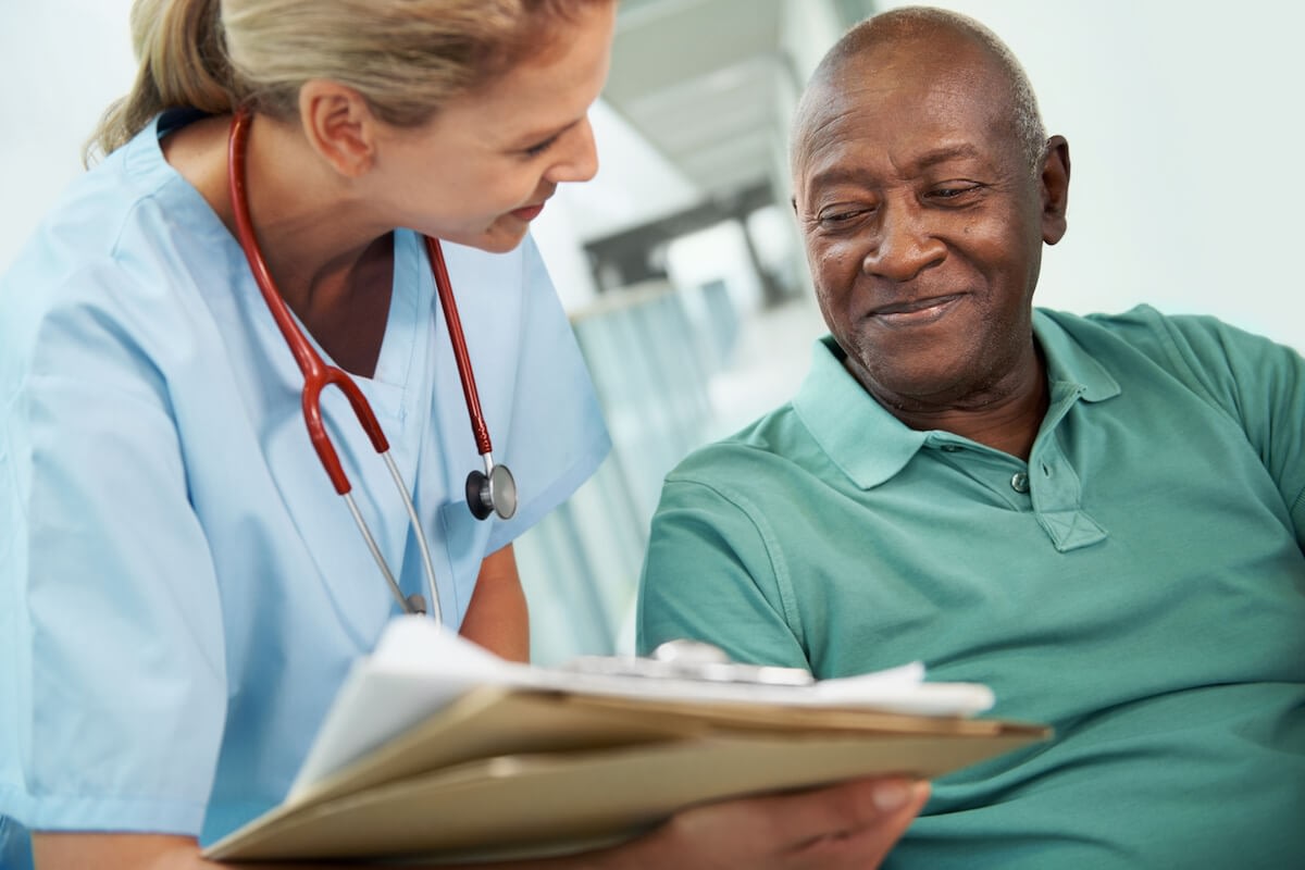 Nurse reviewing chart with senior male patient