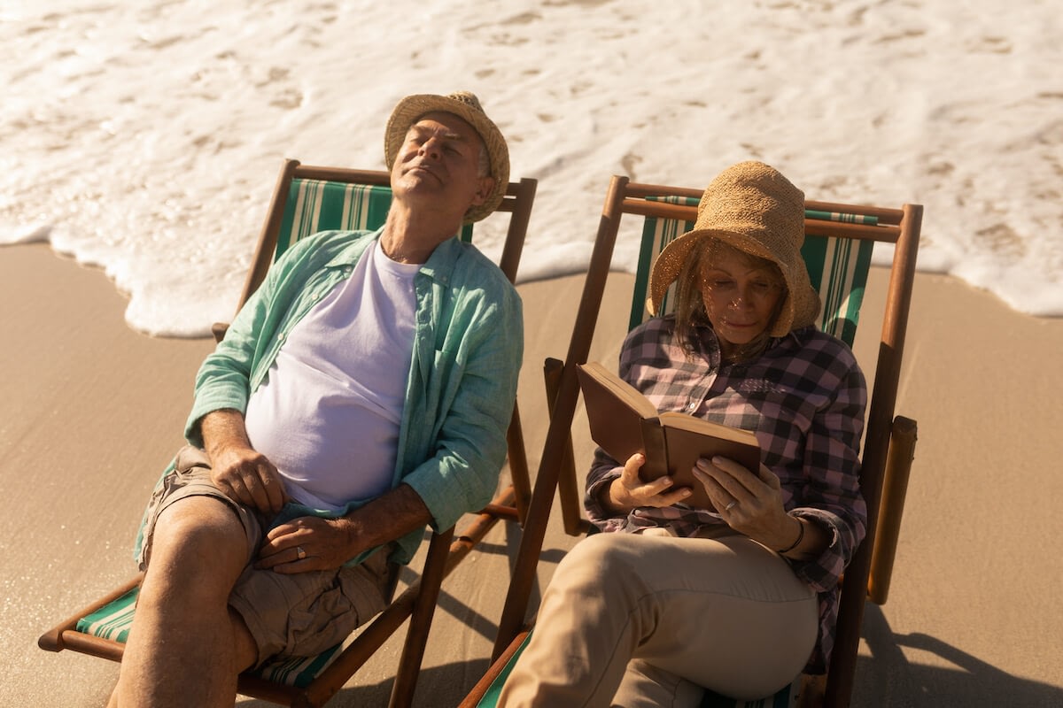 Older couple relaxing on beach chairs by ocean
