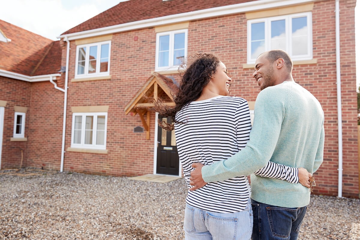 Couple embracing in front of new brick home