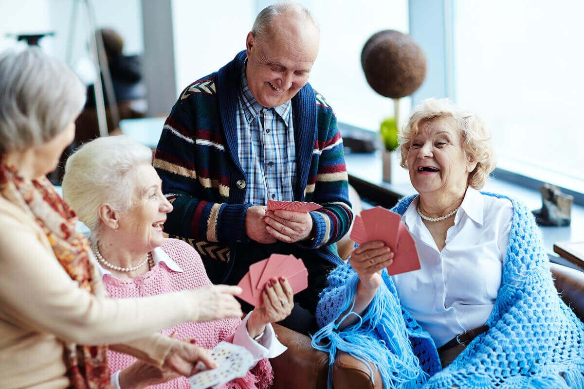 Seniors laughing while playing cards together indoors