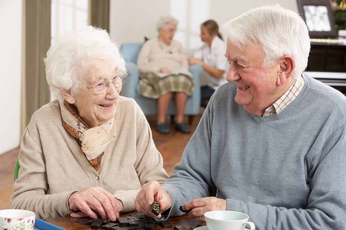 Elderly couple playing dominoes at table