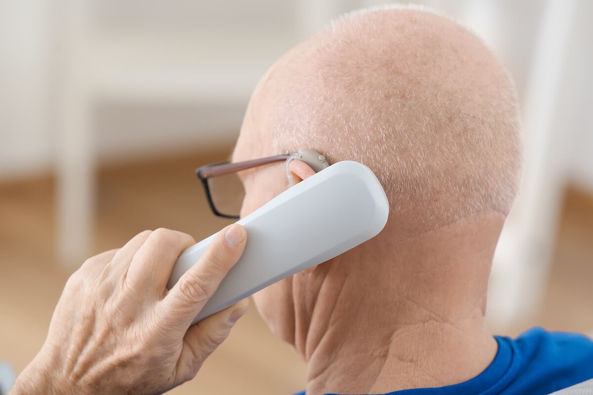 Elderly man using phone with hearing aid