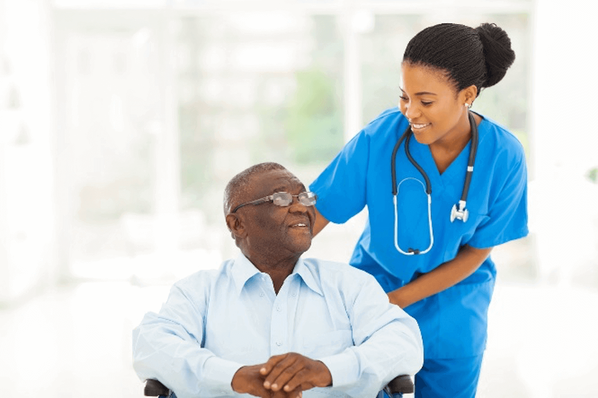 Nurse assisting elderly man in wheelchair