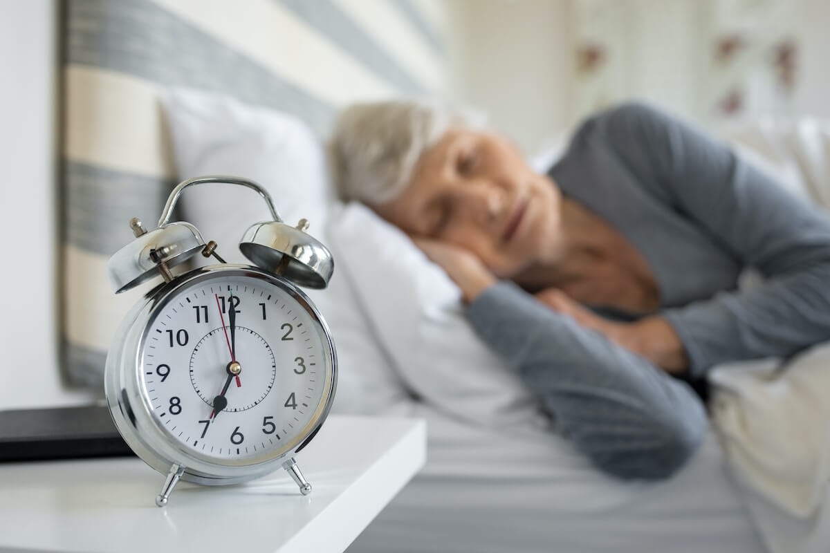 Alarm clock on bedside table, woman sleeping