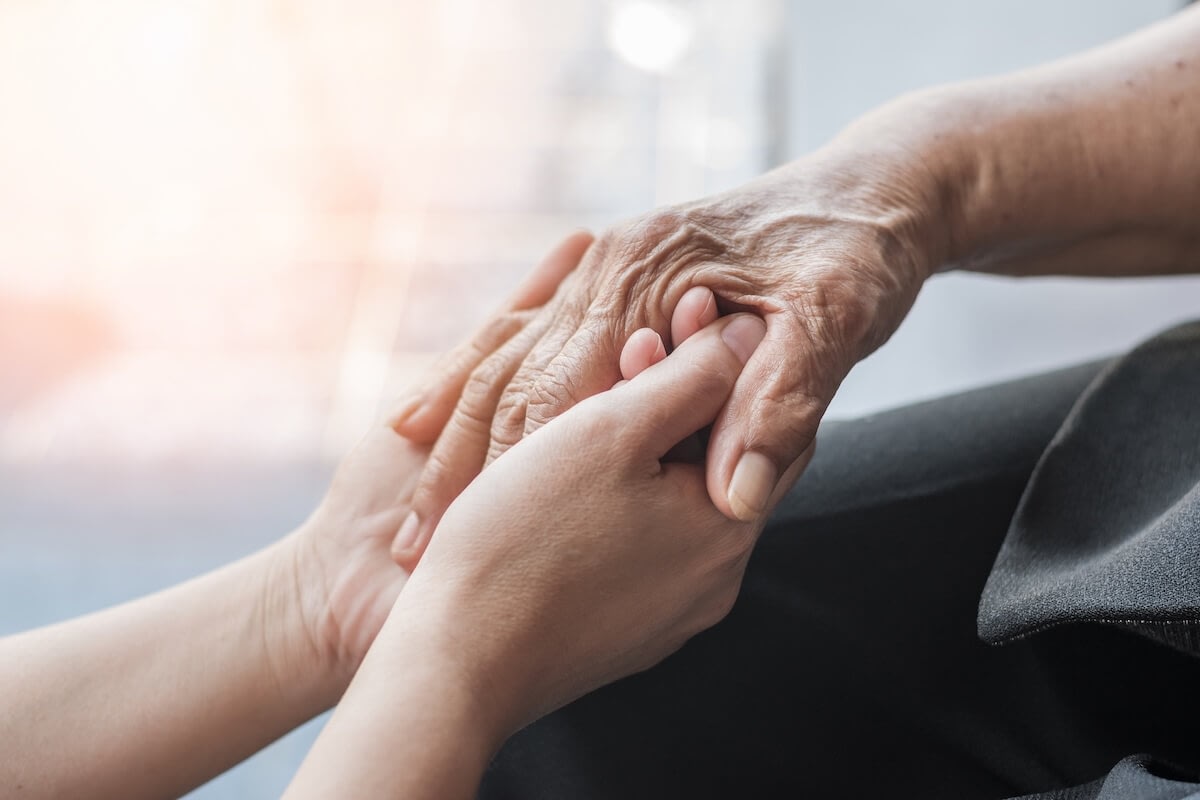 Young person holding elderly person's hand