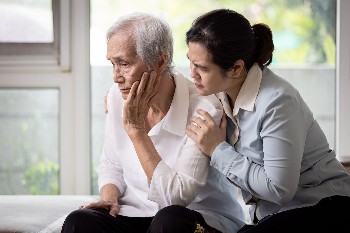 Woman comforting elderly man by window